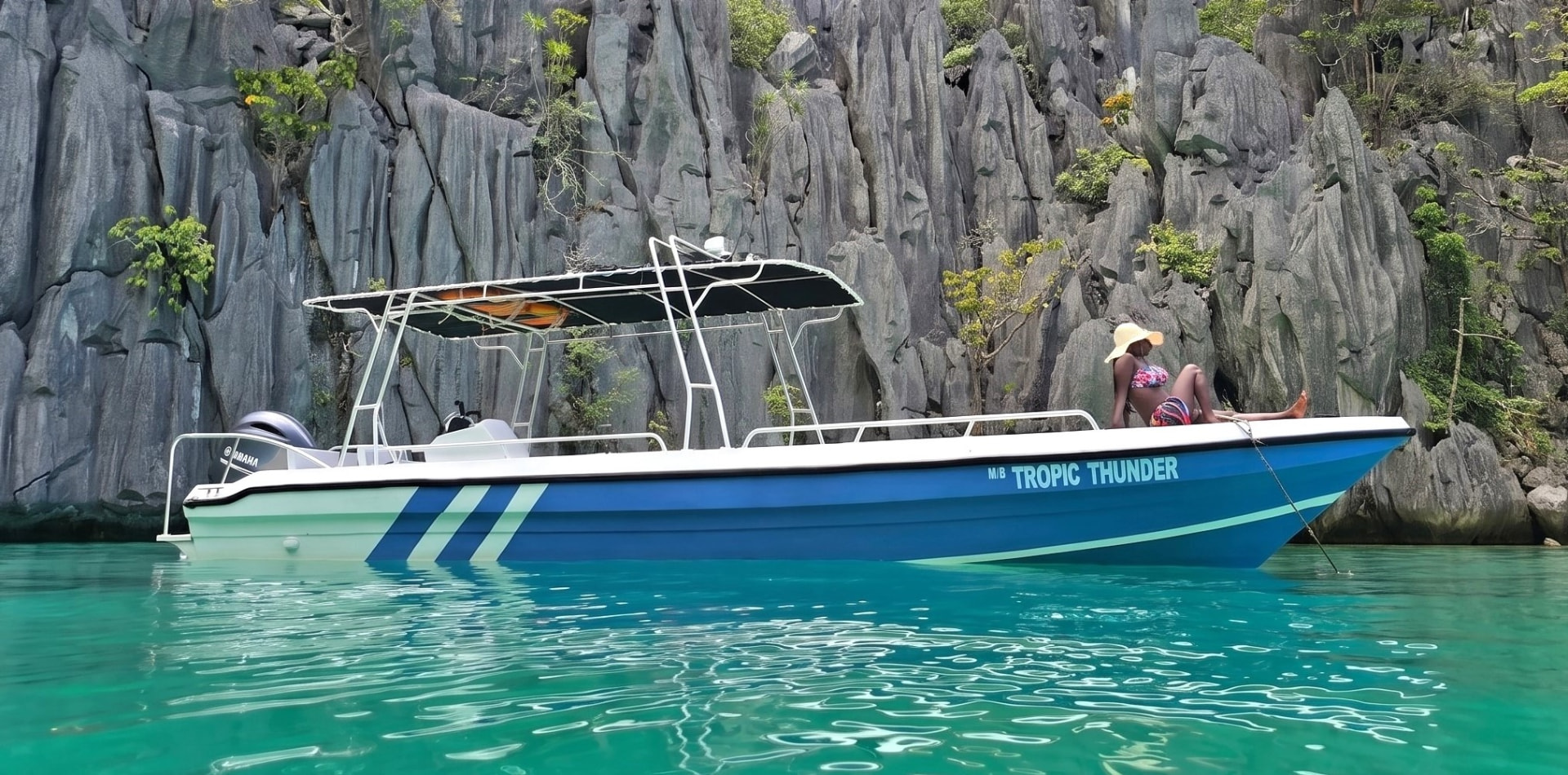 Guest celebrating on the bow of M/B Tropic Thunder in front of the limestone cliffs of Cadlao Lagoon